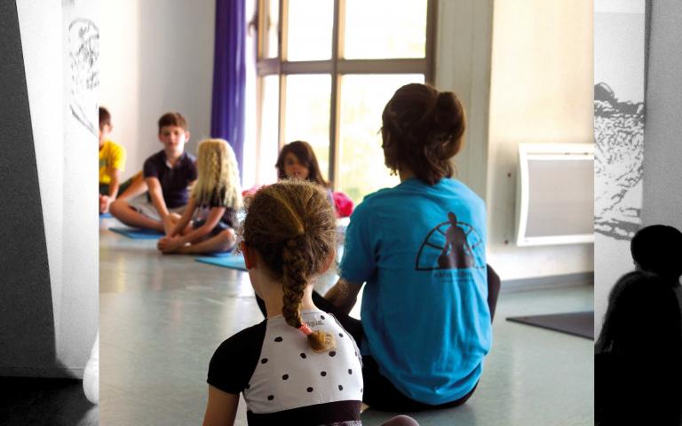 Photo représentant un professeur enseignant le yoga à des enfants